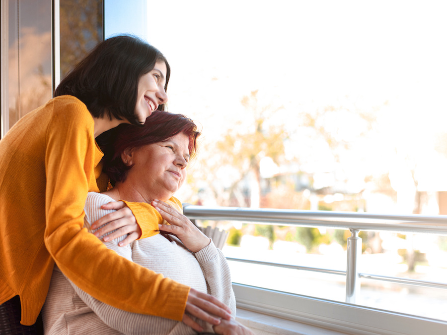 Happy senior mother and adult daughter looking at the view through the window. Happy senior mother and adult daughter looking at the view through the window.